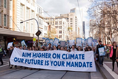 young people rallying behind an aycc banner declaring "aim higher on climate, our future is your mandate"